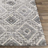 Close-up of the Moruya Area Rug. Beige, charcoal, and cream diamond pattern with a textured, machine-woven construction. Front