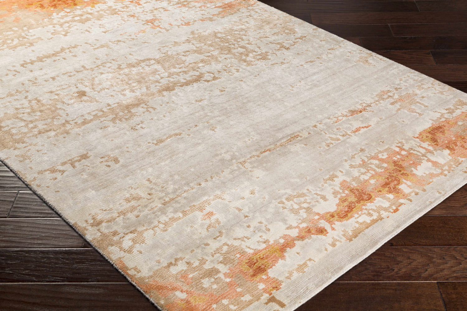 Close up of Mossyrock Premium Rug. Contemporary design in brick red, camel, cream, and tan on dark wood floor. Corner