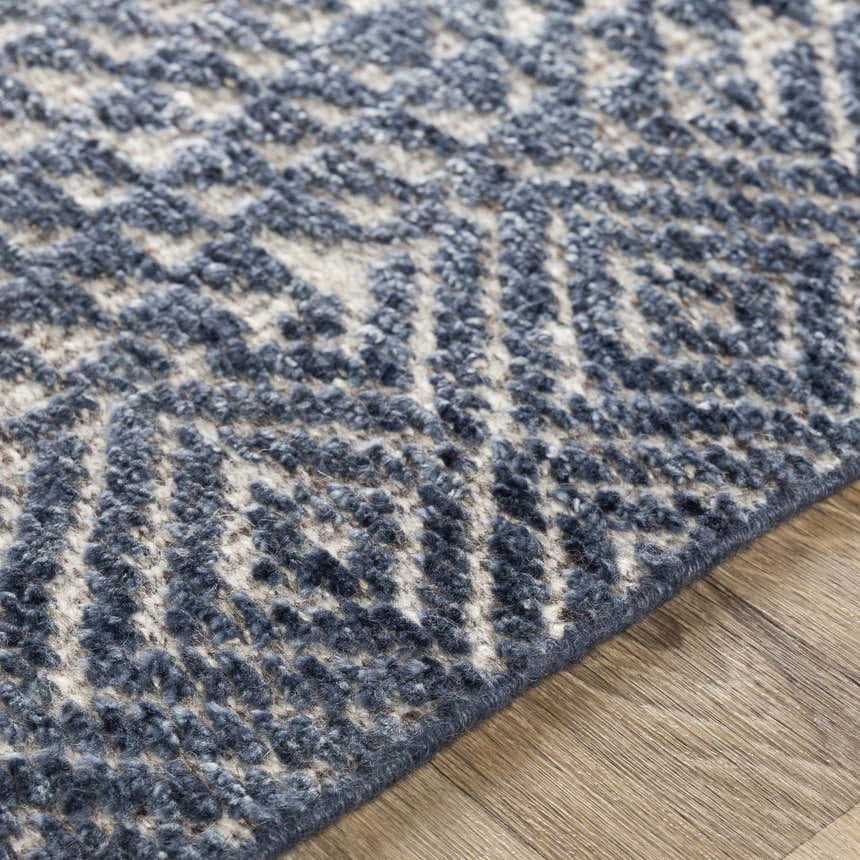 Close-up of the hand-knotted Moyne Area Rug. Charcoal, dark blue, and white geometric pattern. Bohemian style. Pile