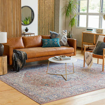 Living room scene with a Cream Rust Maribojoc Medallion Washable Area Rug, leather sofa, and light wood accents. Roomscene-Rectangle