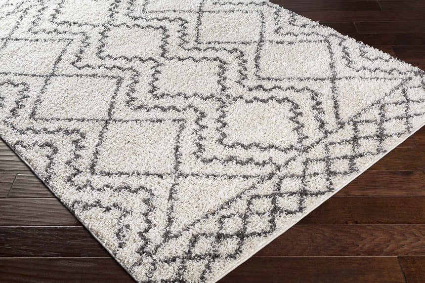 Close-up of the Mooroolbark Area Rug, a shaggy rug with a geometric gray pattern on a cream background. Corner