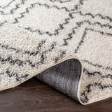 Close-up of the Mooroolbark Area Rug. Ivory shag rug with a gray geometric pattern. Perfect for a bathroom or kitchen. Fold