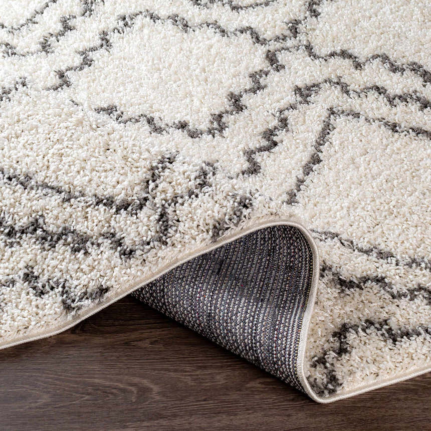 Close-up of the Mooroolbark Area Rug. Ivory shag rug with a gray geometric pattern. Perfect for a bathroom or kitchen. Fold
