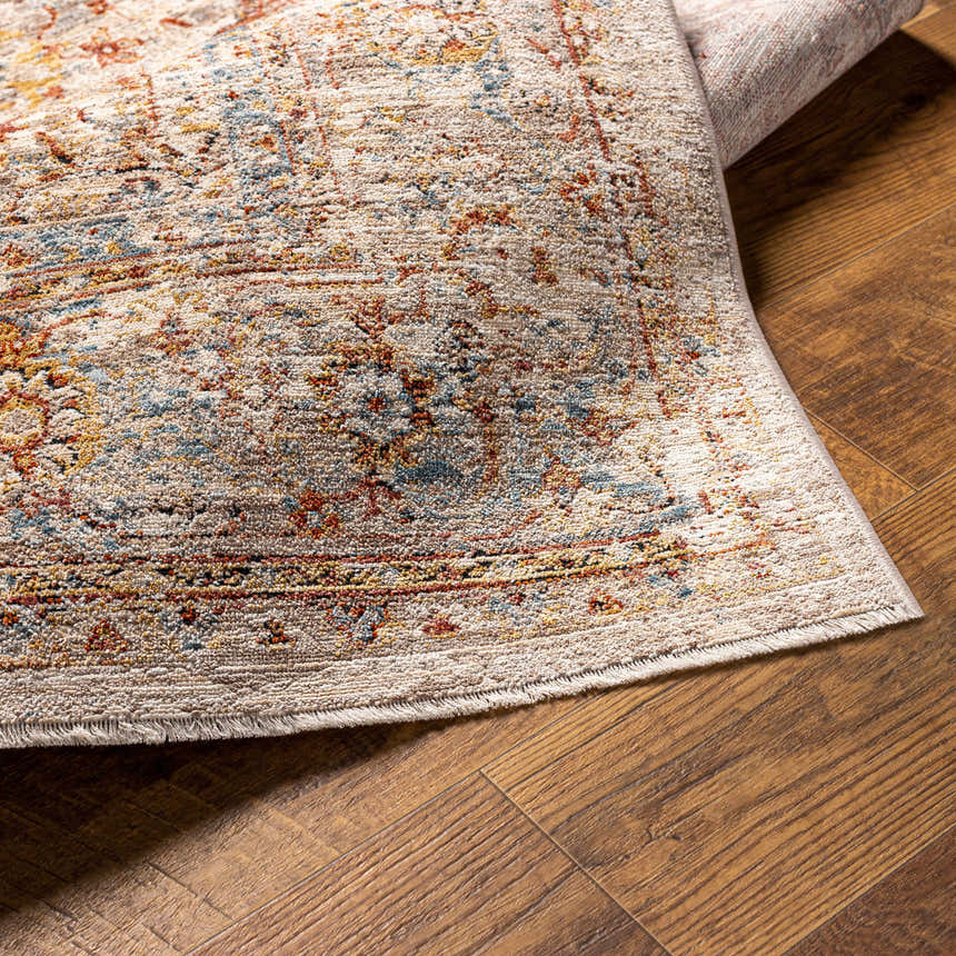 Close-up of the Marieville Luxe Performance Rug showing its cream, brick red, denim, and mustard oriental pattern. Fold