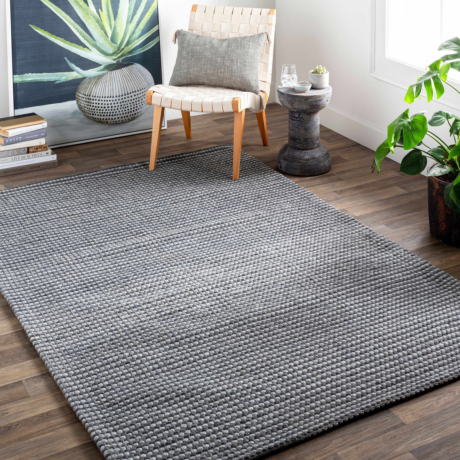 Contemporary living room scene with a gray hand woven Mulgoa Area Rug, chair, side table, and plant. Roomscene-Rectangle