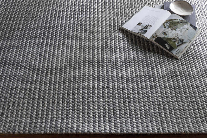 Close-up of the hand woven Mulgoa Area Rug. Medium gray rug with a contemporary design and textured wool and polyester feel. Styleshot