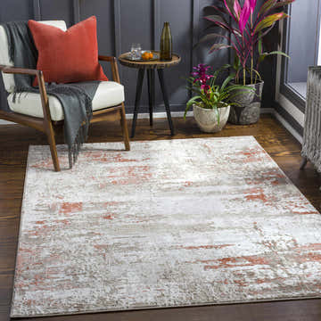 Living room scene with a Musabeyli Area Rug in brick red, cream, and beige, styled with a chair, side table, and plants. Roomscene-Rectangle