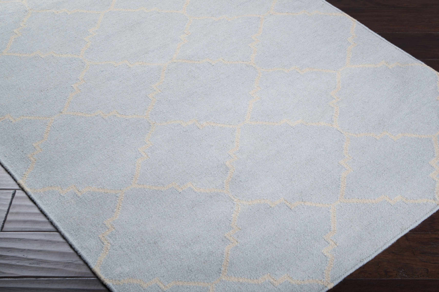 Close up of the hand woven Nadeau Area Rug. Pale blue wool with a tan geometric pattern. Corner