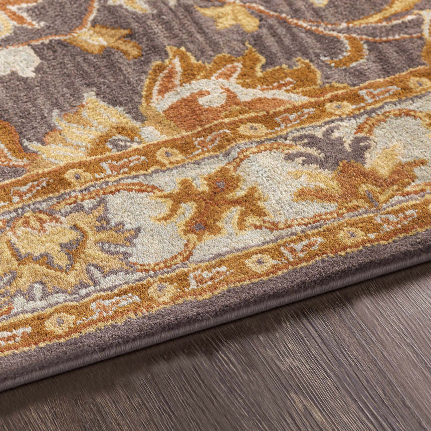 Close up of the hand-tufted Cherryfield 1004 wool rug. Features beige, burnt orange, and charcoal floral pattern. Fold
