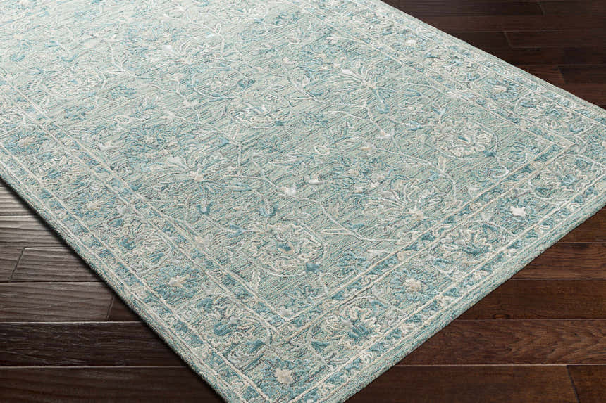 Close-up of the Neavitt Wool & Faux Silk Rug in aqua. Hand-tufted rug with traditional floral pattern and border. Corner