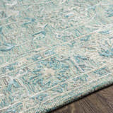 Close-up of the Neavitt Wool & Faux Silk Rug. Aqua, beige, and gray tones create a textured, traditional pattern. Texture