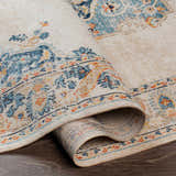 Close-up of the rolled Neepawa Area Carpet. Cream rug with blue, orange, and brown traditional-style pattern. Fold