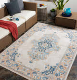 Outdoor patio scene with a Neepawa Area Carpet in aqua, cream, and orange, styled with wicker furniture and stone flooring. Roomscene-Rectangle