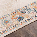 Close-up of the Neepawa Area Carpet showing the cream, blue, and orange traditional-style pattern and soft texture. Texture