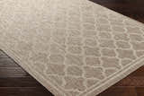 Close-up of the Noam Tan Indoor & Outdoor Rug showing a geometric trellis pattern in tan and beige on dark wood floors. Corner