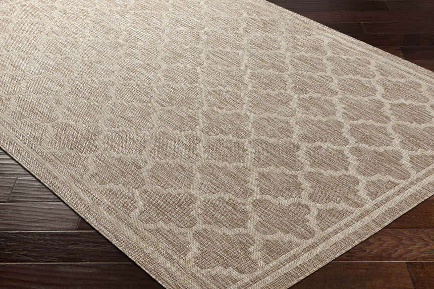 Close-up of the Noam Tan Indoor & Outdoor Rug showing a geometric trellis pattern in tan and beige on dark wood floors. Corner