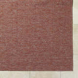 Close-up of the Nuela Burgundy Area Rug showing its woven texture and diamond pattern on tile flooring. Corner