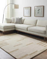 Living room scene with a beige Nadav Area Rug, sectional sofa, and minimalist art. Roomscene-Rectangle