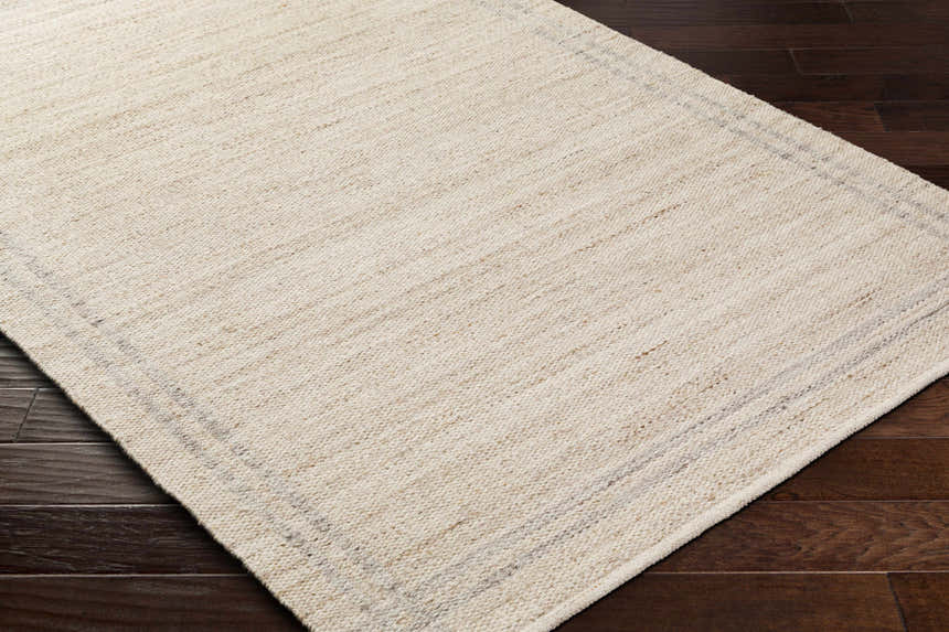 Close-up of the hand woven Nimue Tan Area Rug showing its ivory, tan colors and subtle pattern. Corner