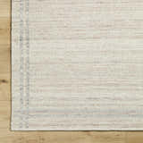 Close-up of the hand woven Nimue Tan Area Rug. Ivory and tan wool rug with a subtle stripe pattern. Corner