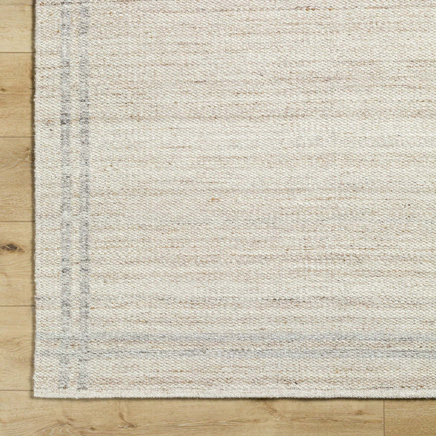 Close-up of the hand woven Nimue Tan Area Rug. Ivory and tan wool rug with a subtle stripe pattern. Corner