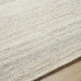 Close-up of the hand-woven Nimue Tan Area Rug. Ivory and tan wool fibers show texture and pattern. Texture