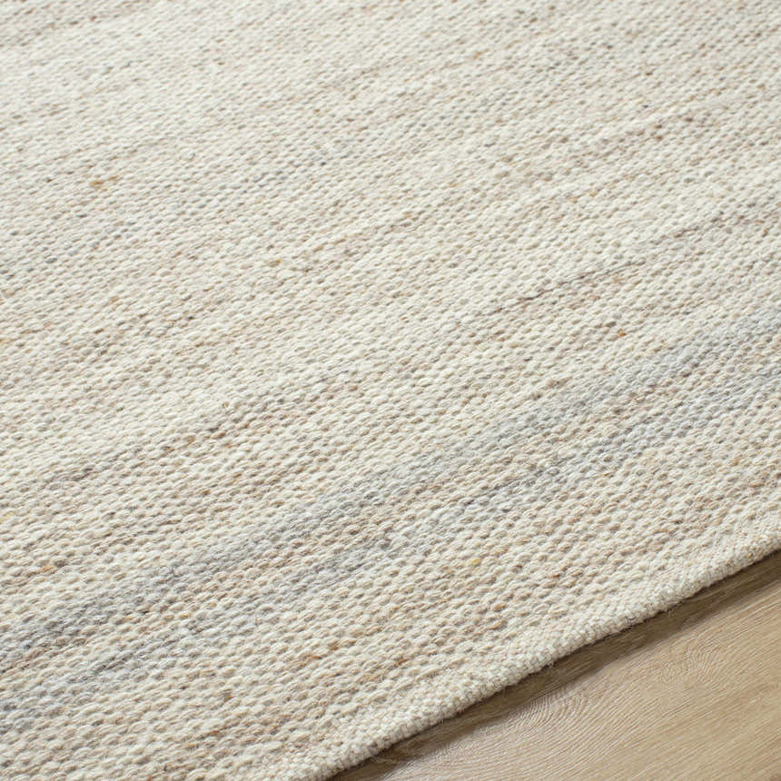 Close-up of the hand-woven Nimue Tan Area Rug. Ivory and tan wool fibers show texture and pattern. Texture