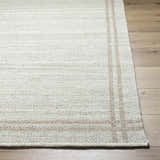 Close-up of the hand-woven Nimue Area Rug. Ivory and tan wool rug with a subtle striped pattern and textured weave. Front