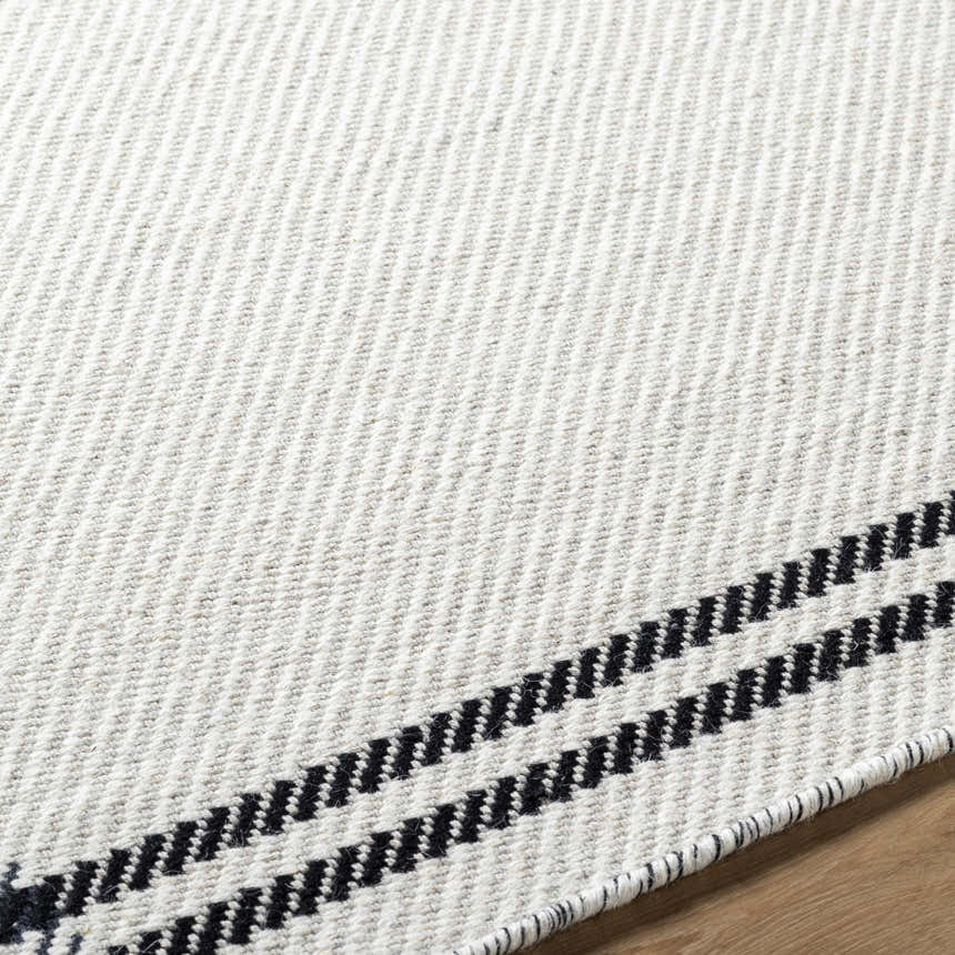 Close up of the hand woven Nimue Cream & Blue Bordered Area Rug showing wool texture and striped border detail. Texture
