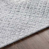 Close-up of the Boxholm Gray Rug showing its hand-tufted texture and subtle geometric pattern on dark wood floors. Texture
