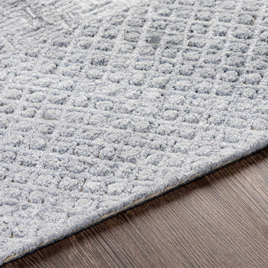 Close-up of the Boxholm Gray Rug showing its hand-tufted texture and subtle geometric pattern on dark wood floors. Texture