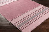 Close-up of the hand woven Northorpe Area Rug. Burgundy, pink, and white farmhouse style design. Corner