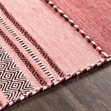 Close up of the hand woven Northorpe Area Rug. Pink rug with geometric and striped patterns in burgundy, dark pink, and white. Texture