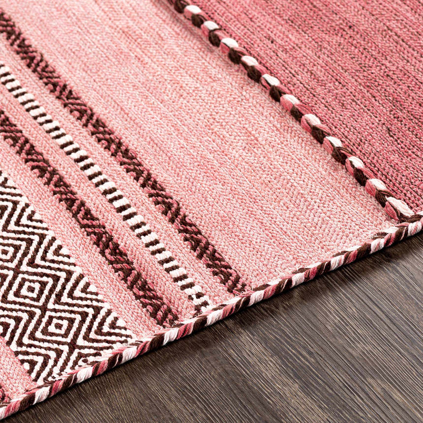 Close up of the hand woven Northorpe Area Rug. Pink rug with geometric and striped patterns in burgundy, dark pink, and white. Texture