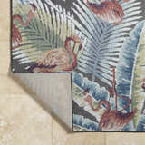 Close up of Nayan Charcoal Area Rug showing flamingo and palm leaf coastal design in blue, cream, olive, and rust colors. Fold
