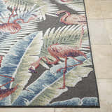 Close-up of Nayan Charcoal Area Rug featuring a coastal design with flamingos and tropical leaves in blue, cream, olive, and rust. Front
