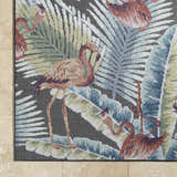 Close-up of Nayan Charcoal Area Rug showing flamingo and tropical leaf design in blue, rust, and cream. Coastal style. Corner