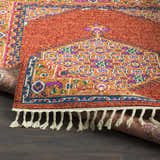 Close-up of the Oban Traditional Rug showing camel, coral, and blue tones with a detailed pattern and fringe. Fold