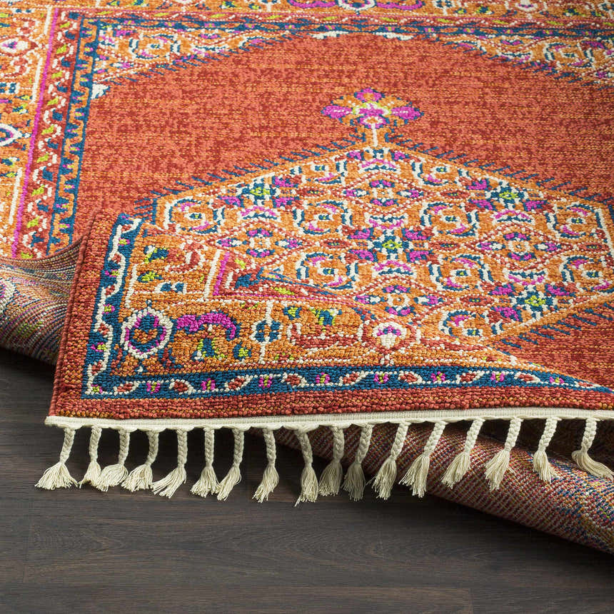 Close-up of the Oban Traditional Rug showing camel, coral, and blue tones with a detailed pattern and fringe. Fold