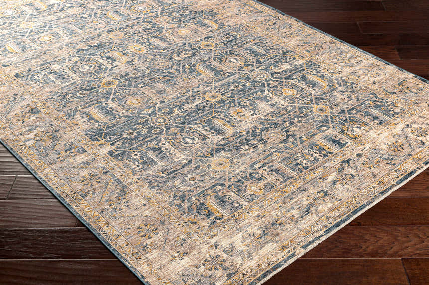 Close-up of Odala Luxe Performance Rug. Bohemian style rug in denim, beige, and mustard on dark wood floor. Corner