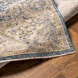 Close-up of the Odala Luxe Performance Rug showing its traditional design, denim blue, beige, and mustard colors. Fold
