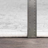 Close-up of Okehampton Area Rug showing pile height with a ruler. Colors are charcoal, light gray, and white. Pile