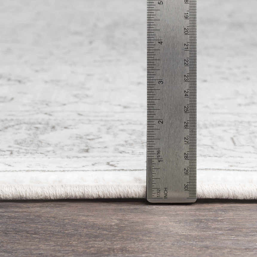 Close-up of Okehampton Area Rug showing pile height with a ruler. Colors are charcoal, light gray, and white. Pile