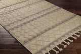 Close-up of the Okurcalar Area Carpet. Tan and gray jute-wool rug with a geometric pattern and braided tassels. Corner