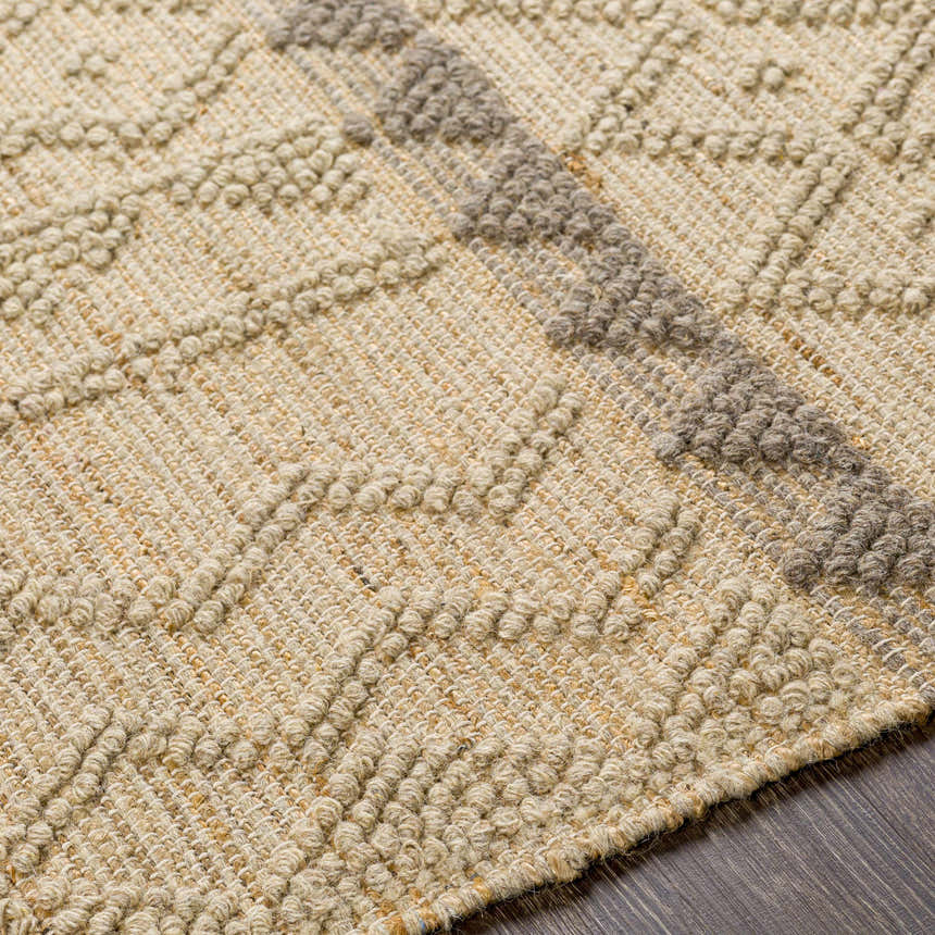 Close-up of the Okurcalar Area Carpet. Tan jute and gray wool create a textured, hand-woven diamond pattern. Texture