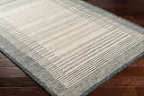 Close-up of the Omeo Wool Area Rug. Bone and dark gray stripes create a modern, Scandinavian design. Hand-tufted texture. Corner