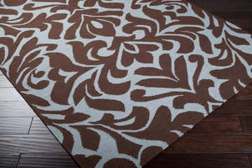 Close up of the Oppelo Area Rug, a hand woven wool rug in dark brown and sage with a contemporary floral pattern. Corner