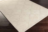 Close-up of the beige Orick Hand Loomed Wool Area Rug showing its geometric pattern and texture on dark wood floors. Corner