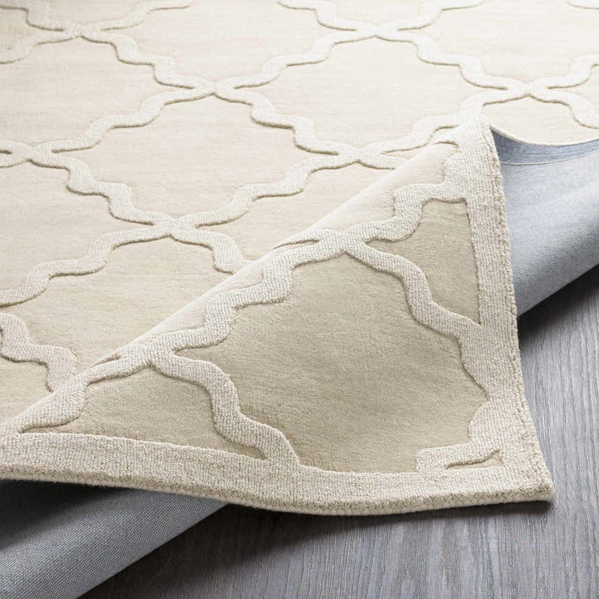 Close-up of the beige Orick Hand Loomed Wool Area Rug showing the geometric trellis pattern and hand-loomed texture. Fold