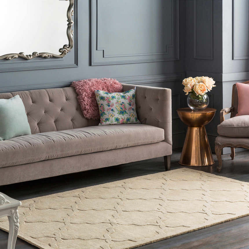 Living room scene with a beige Orick Hand Loomed Wool Area Rug, tufted sofa, and copper accent table. Roomscene-Rectangle